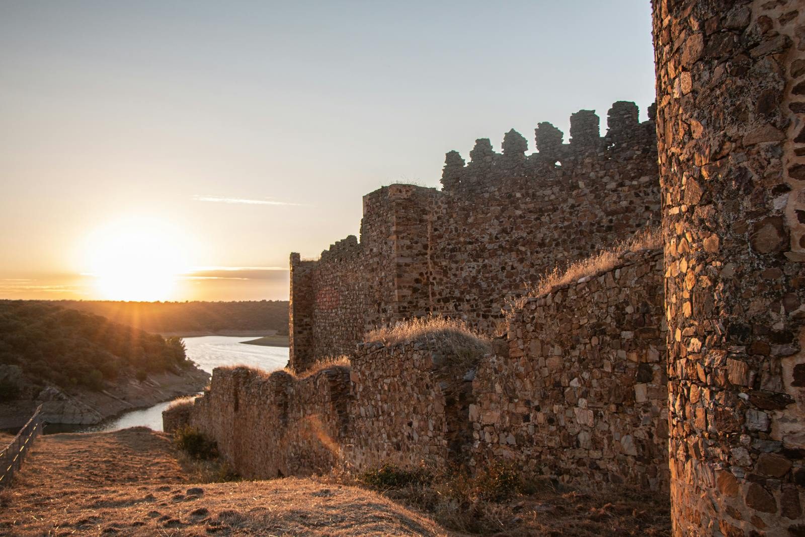 Majestic medieval castle ruins with stone walls at sunset, offering a dramatic view.